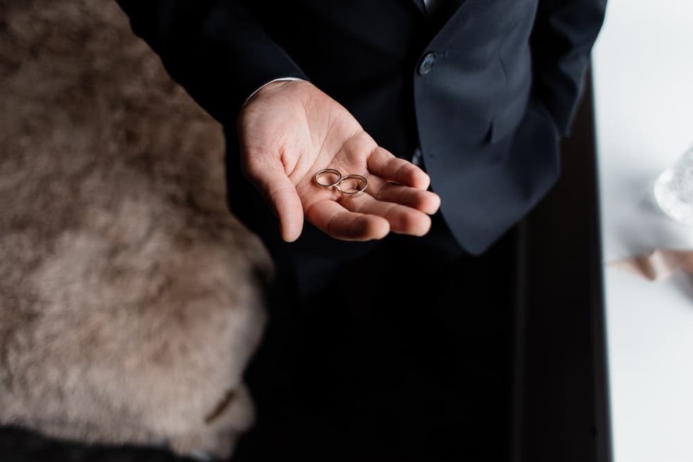 En hånd holder forsigtigt to vielsesringe